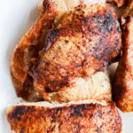 grilled full chicken on platter in pieces with utensils