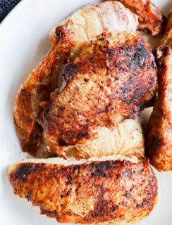 grilled full chicken on platter in pieces with utensils