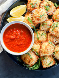 air fryer ravioli on plate with lemon slices, marinara sauce, and fresh basil
