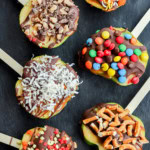 line of sliced fruit with chocolate caramel and other toppings