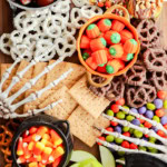 skeleton hands on a sweet treat platter with candies, fruits, and crackers