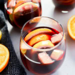 glasses of fruity punch with orange halves and a napkin