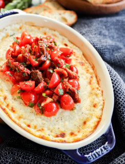 baked goat cheese appetizer in baking dish with tomato topping