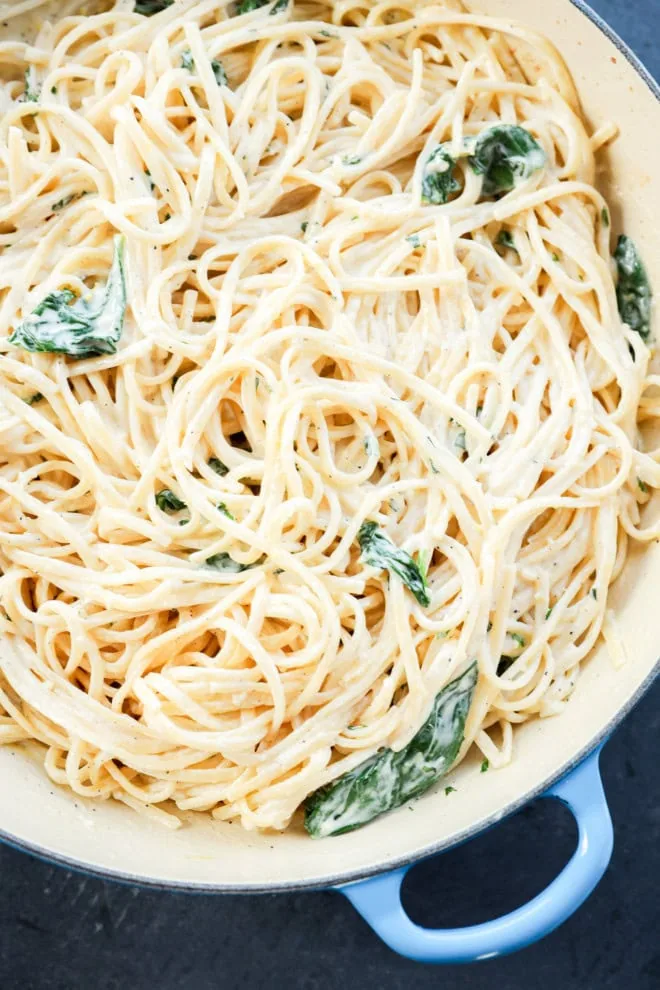 linguine with white cream sauce basil and spinach in a skillet