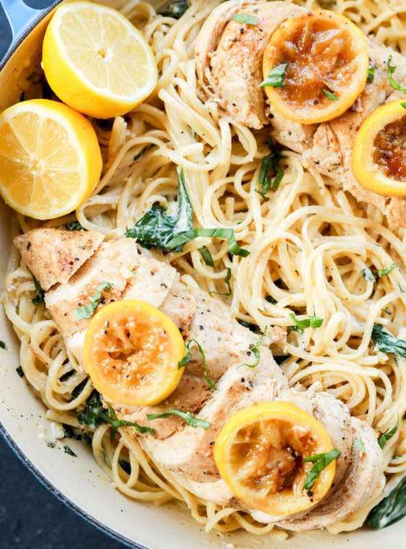 creamy lemon chicken pasta in skillet with fresh lemons