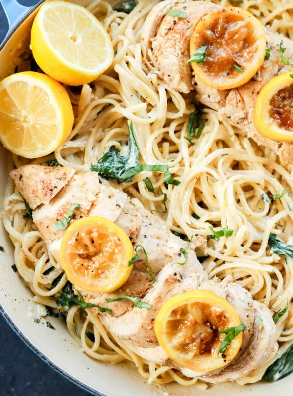 creamy lemon chicken pasta in skillet with fresh lemons