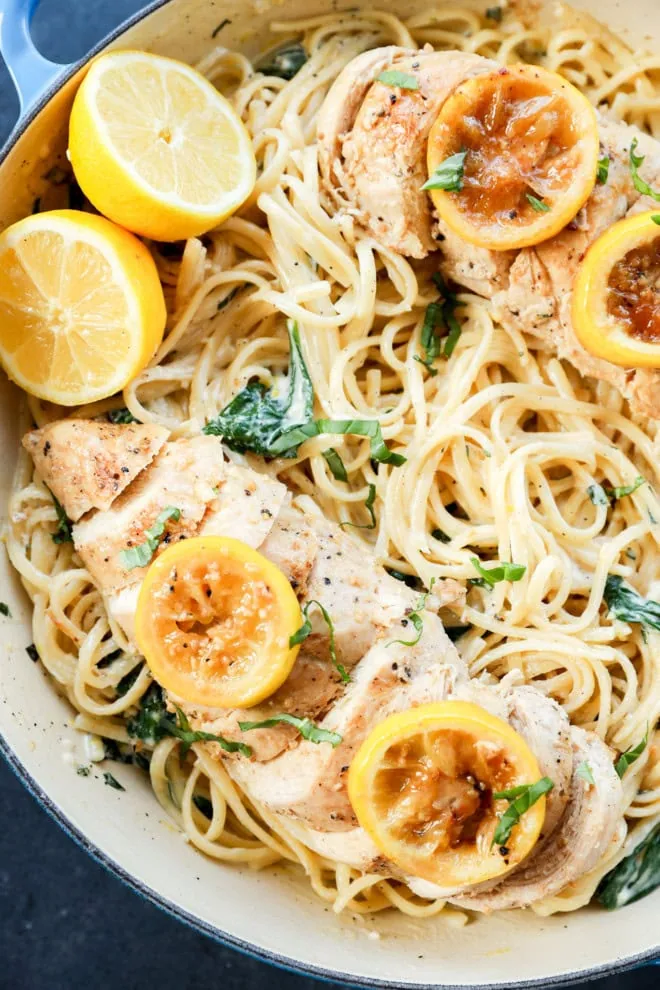 creamy lemon chicken pasta in skillet with fresh lemons