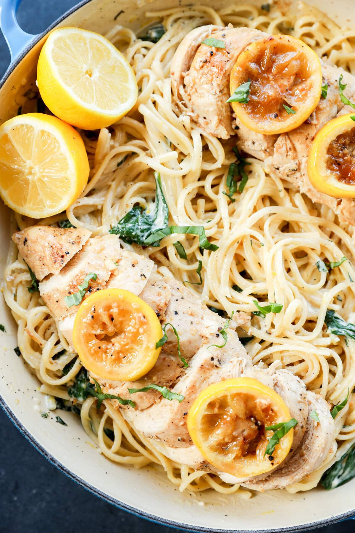 creamy lemon chicken pasta in skillet with fresh lemons