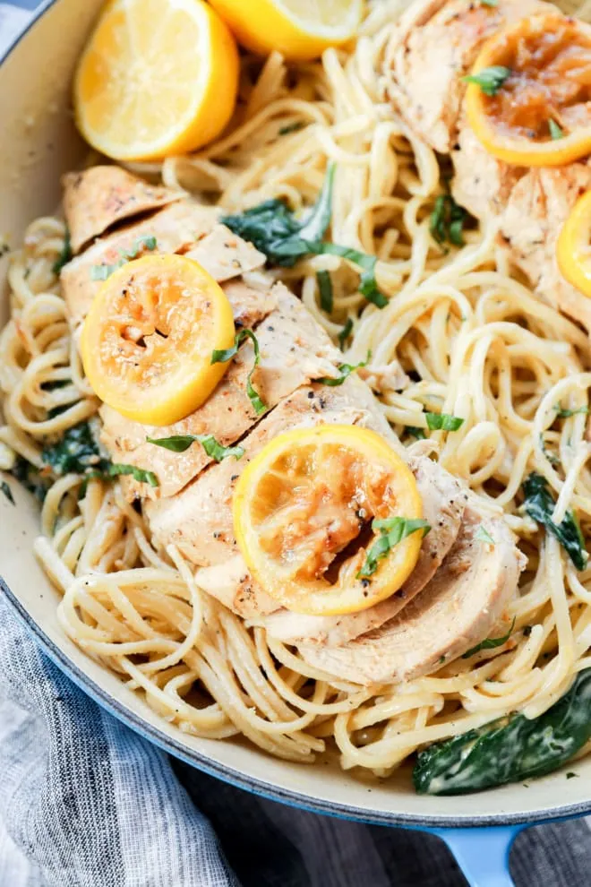 poultry sliced with citrus slices on top of creamy linguine