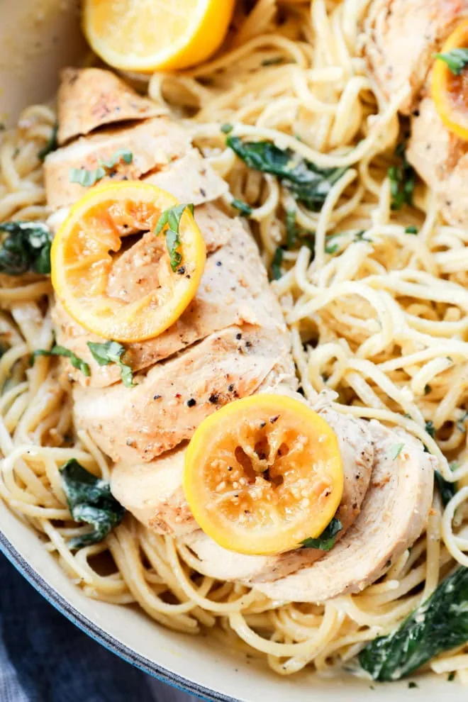 creamy linguine with poultry sliced on top and fresh basil and spinach