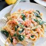 easy creamy fettuccine with seafood and greens on a plate with lemons and a fork