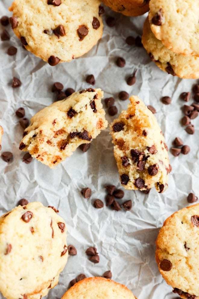 mini chocolate chip muffin in half on parchment paper with mini chocolate chips