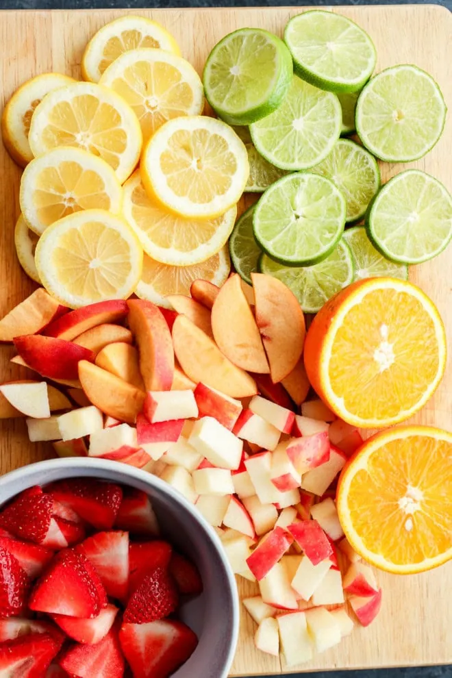 citrus slices and fresh fruit chopped on a wooden cutting board