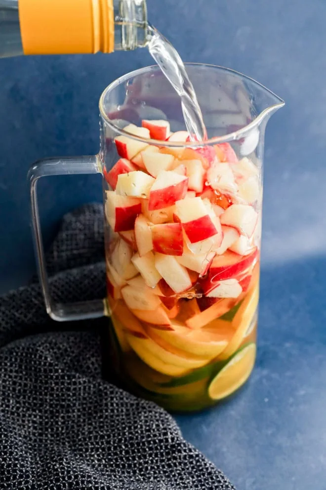 pouring wine into a pitcher with fresh fruit