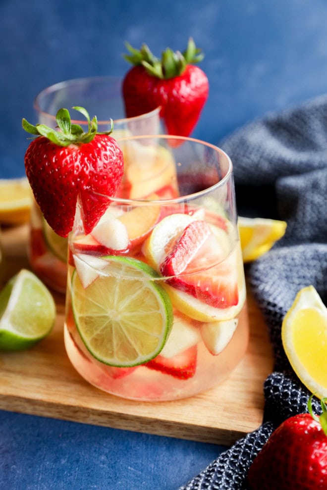 fresh fruit in a glass with wine on a wooden cutting board