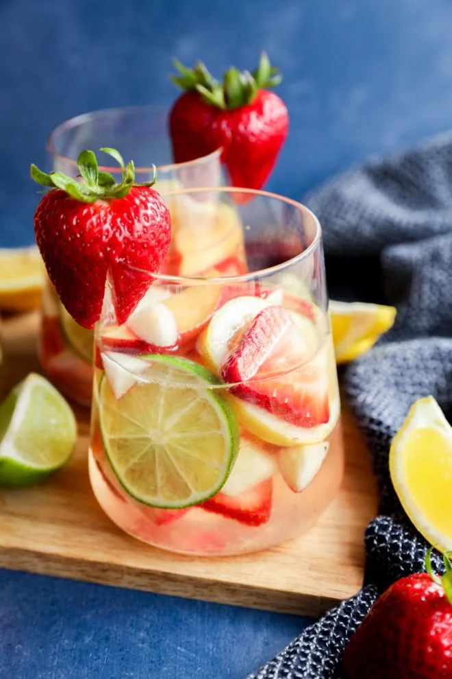 fresh fruit in a glass with wine on a wooden cutting board