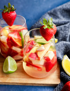 White sangria with white wine, fresh fruit and citrus on wood