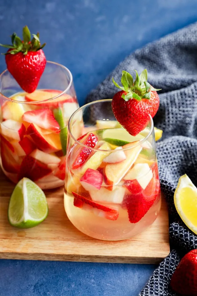 White sangria with white wine, fresh fruit and citrus on wood