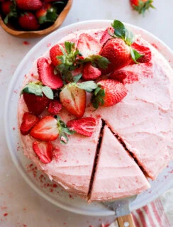 cutting a slice of fresh berry pink dessert with fresh fruit on top