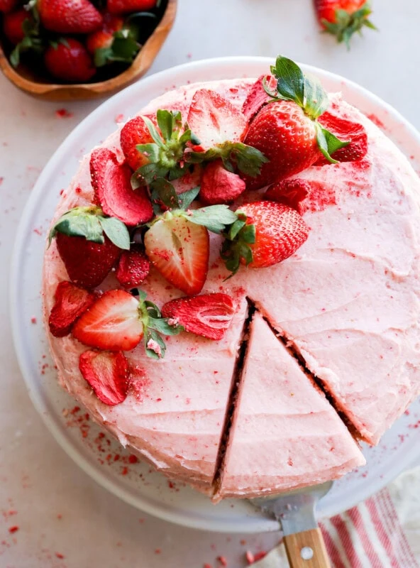 cutting a slice of fresh berry pink dessert with fresh fruit on top