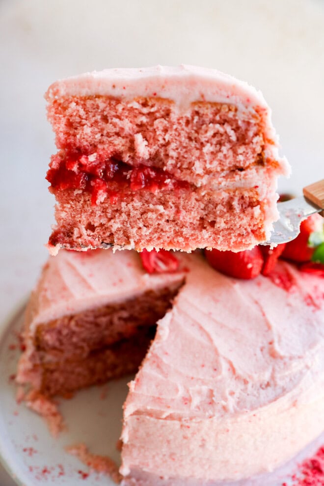 lifting a slice of strawberry cake with strawberry filling off of a cake plate