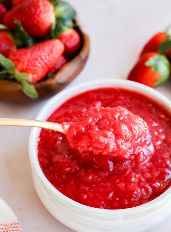 spoon lifting out berry compote from a bowl