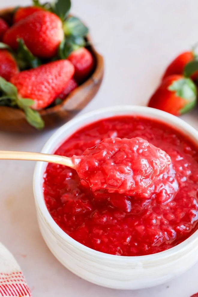 spoon lifting out berry compote from a bowl