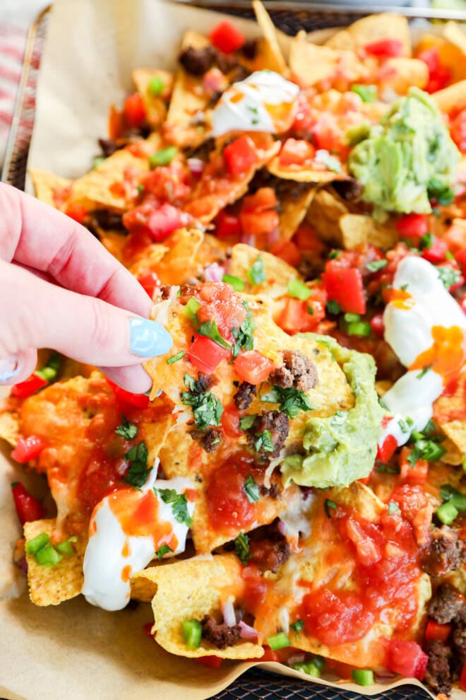 Hand pulling out a mexican appetizer from a pan