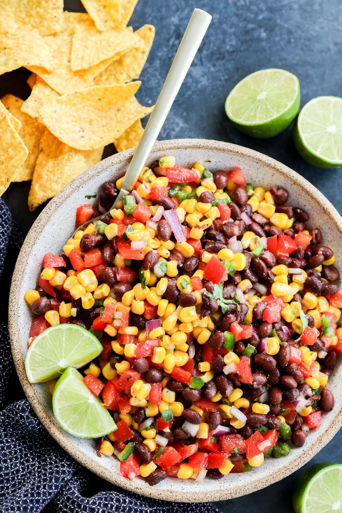 fresh and easy Black bean corn salsa dip in a bowl with a spoon and tortilla chips all around
