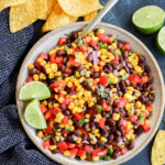 Bowl of fresh vegetables to make an appetizer with chips around and fresh limes