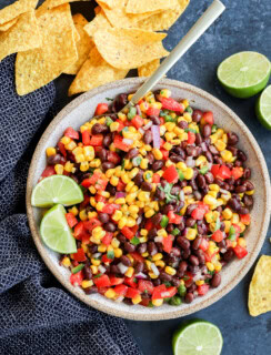 Bowl of fresh vegetables to make an appetizer with chips around and fresh limes