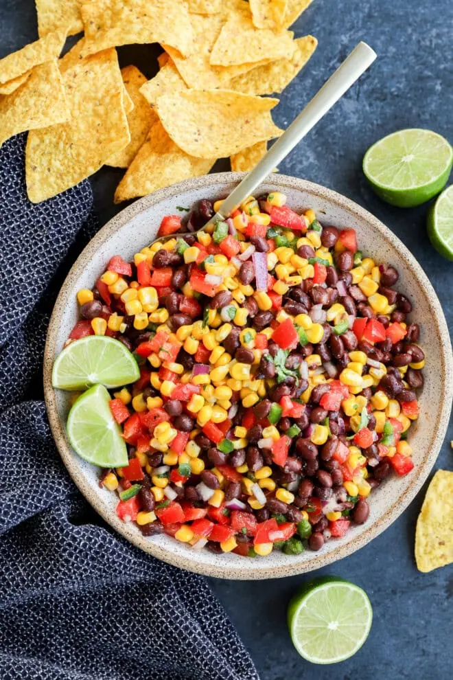 Bowl of fresh vegetables to make an appetizer with chips around and fresh limes