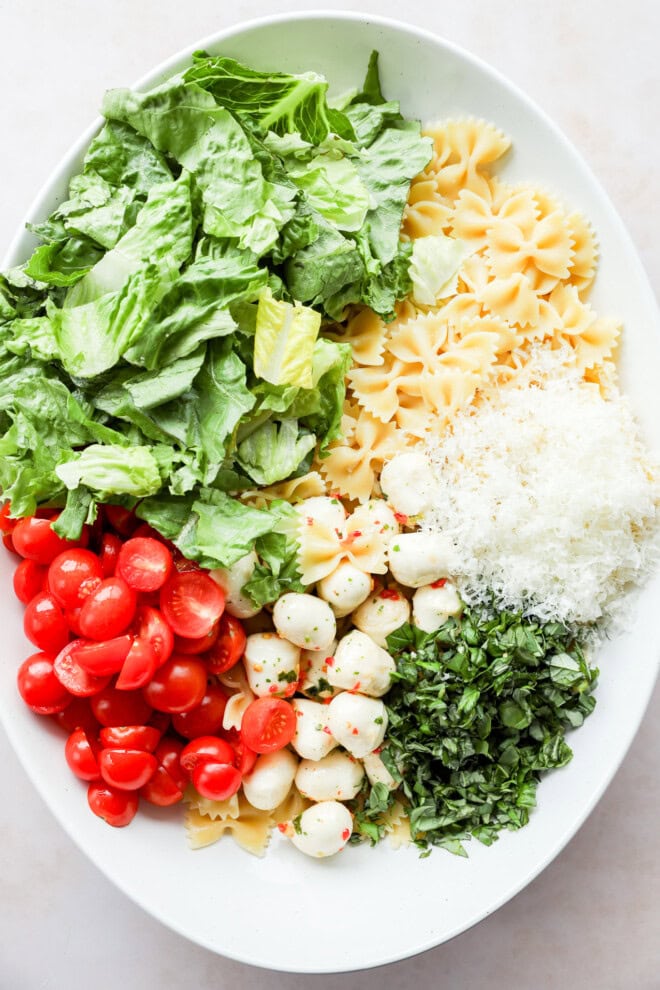 ingredients for caprese bow tie pasta salad in a bowl before stirring