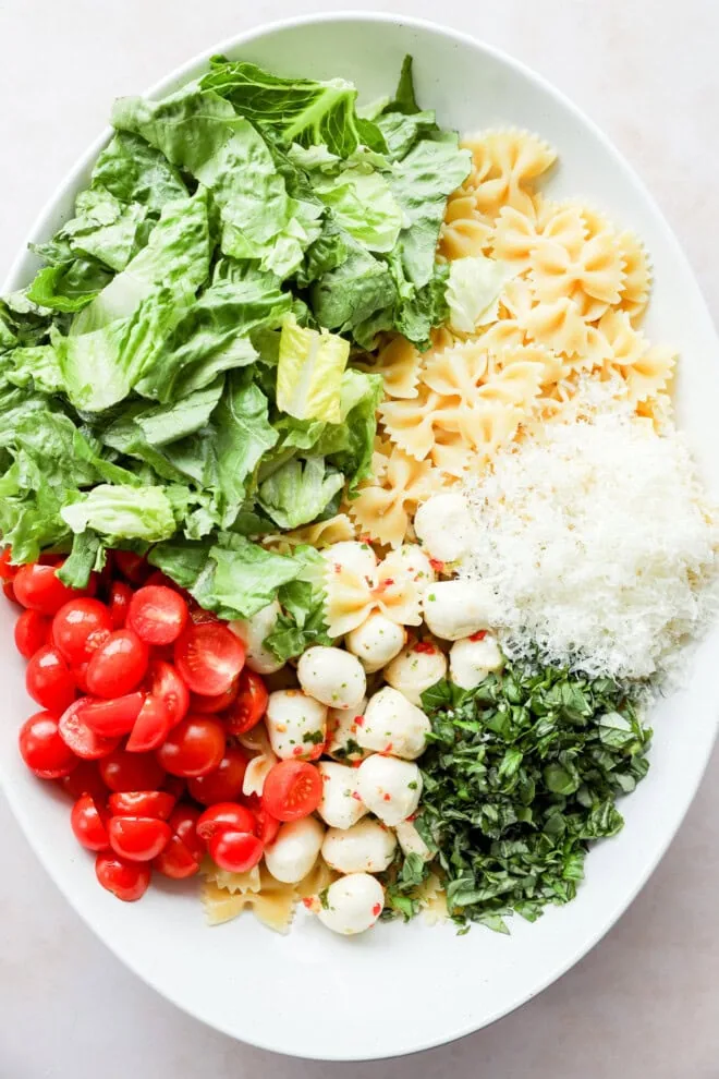 ingredients for caprese bow tie pasta salad in a bowl before stirring