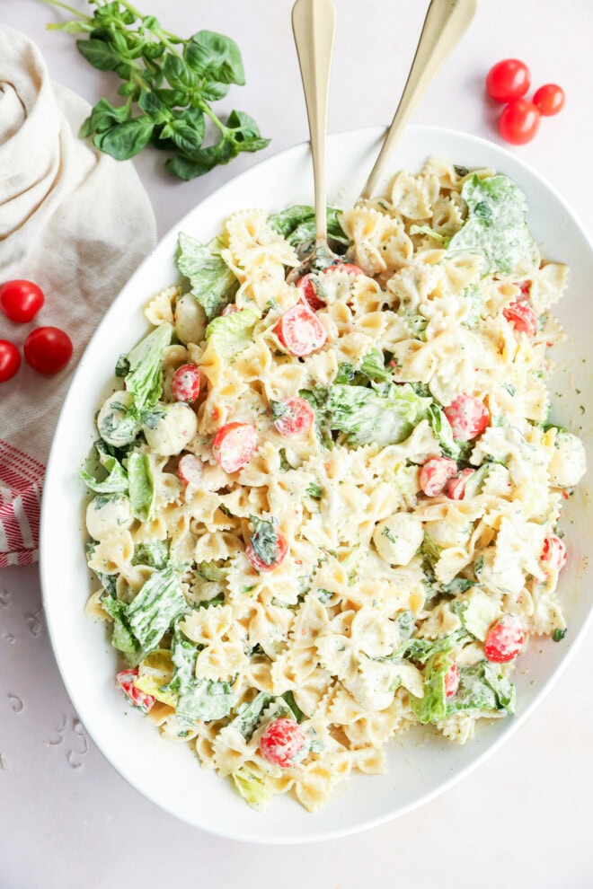 caprese bow tie pasta salad in a bowl with spoons