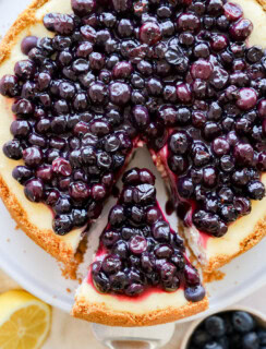 taking a slice out of lemon blueberry cheesecake on a cake stand