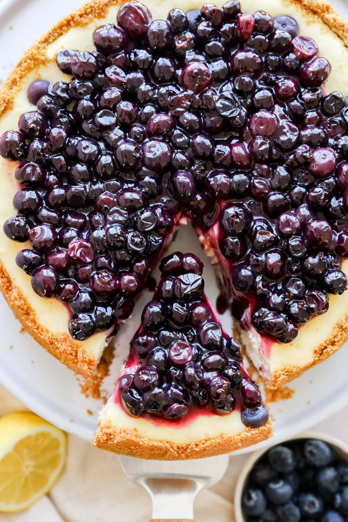 taking a slice out of lemon blueberry cheesecake on a cake stand