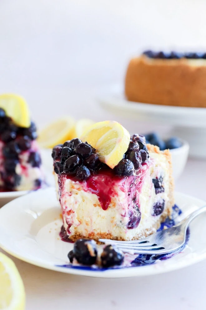 fork on plate with slice of fruity dessert and fresh citrus on top