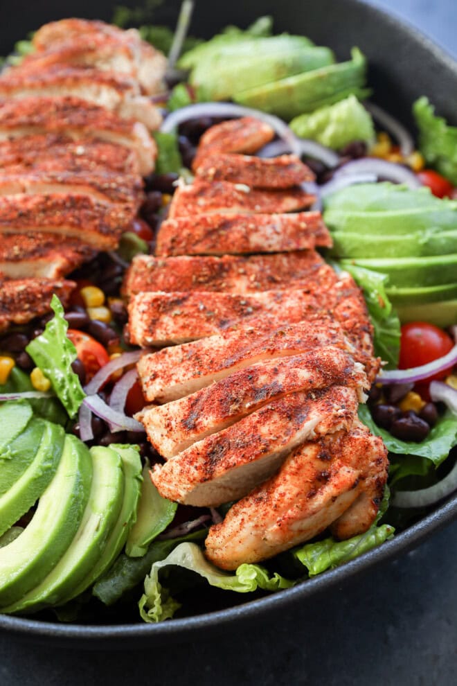 grilled poultry on top of lettuce with sliced avocado