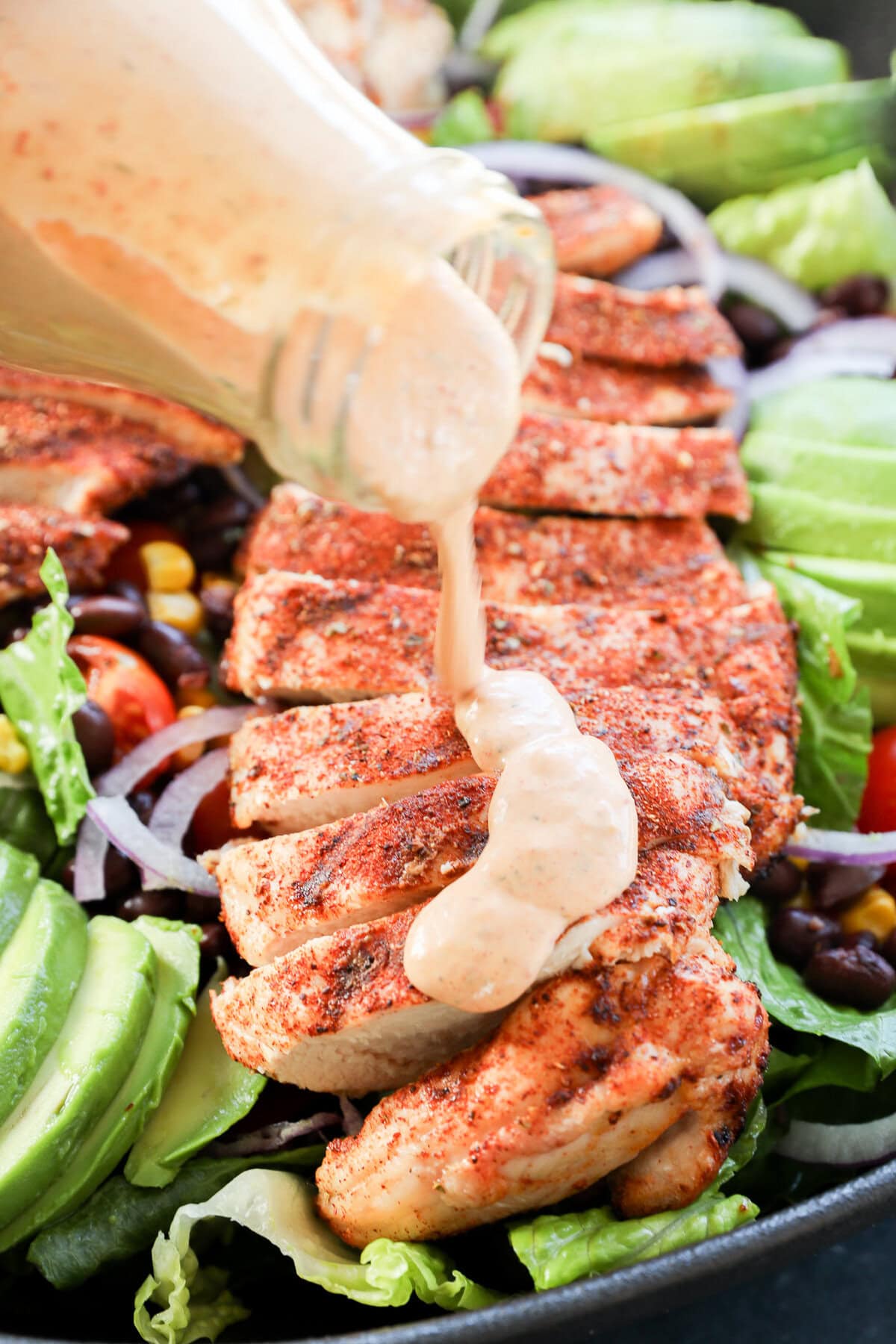 pouring dressing on top of seasoned grilled poultry