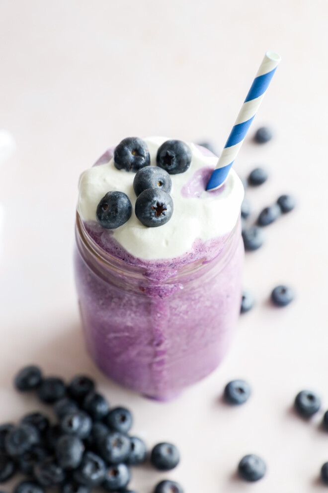 glass of sweet dessert drink with blue striped straw and fresh berries