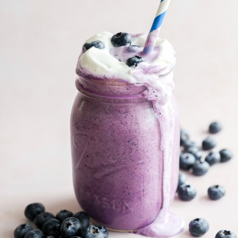 straw in an ice cream drink with fresh berries all around