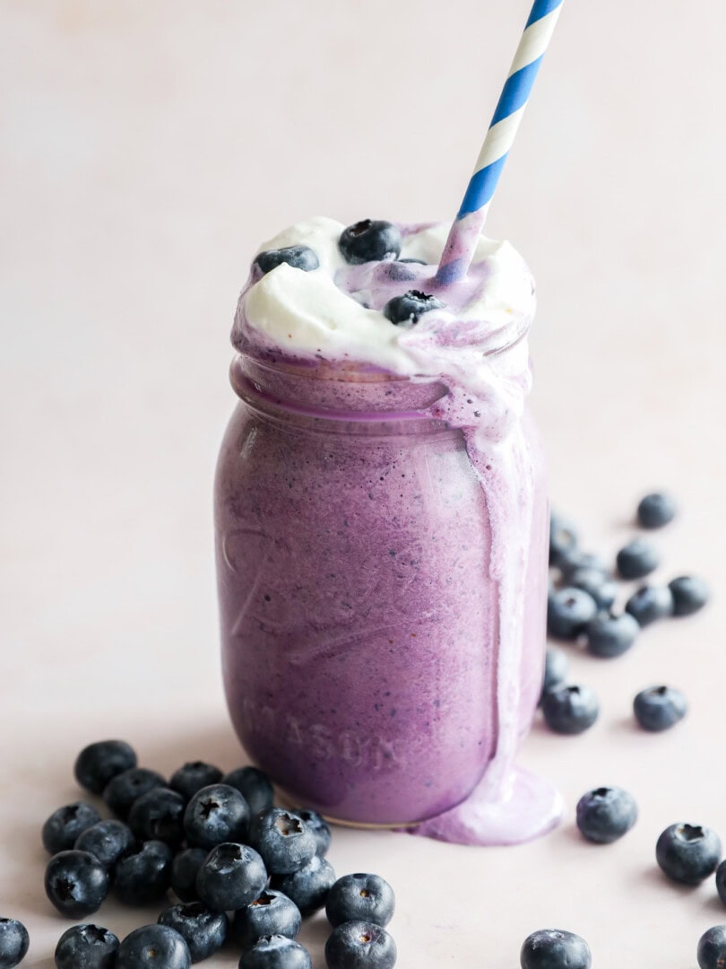 straw in an ice cream drink with fresh berries all around