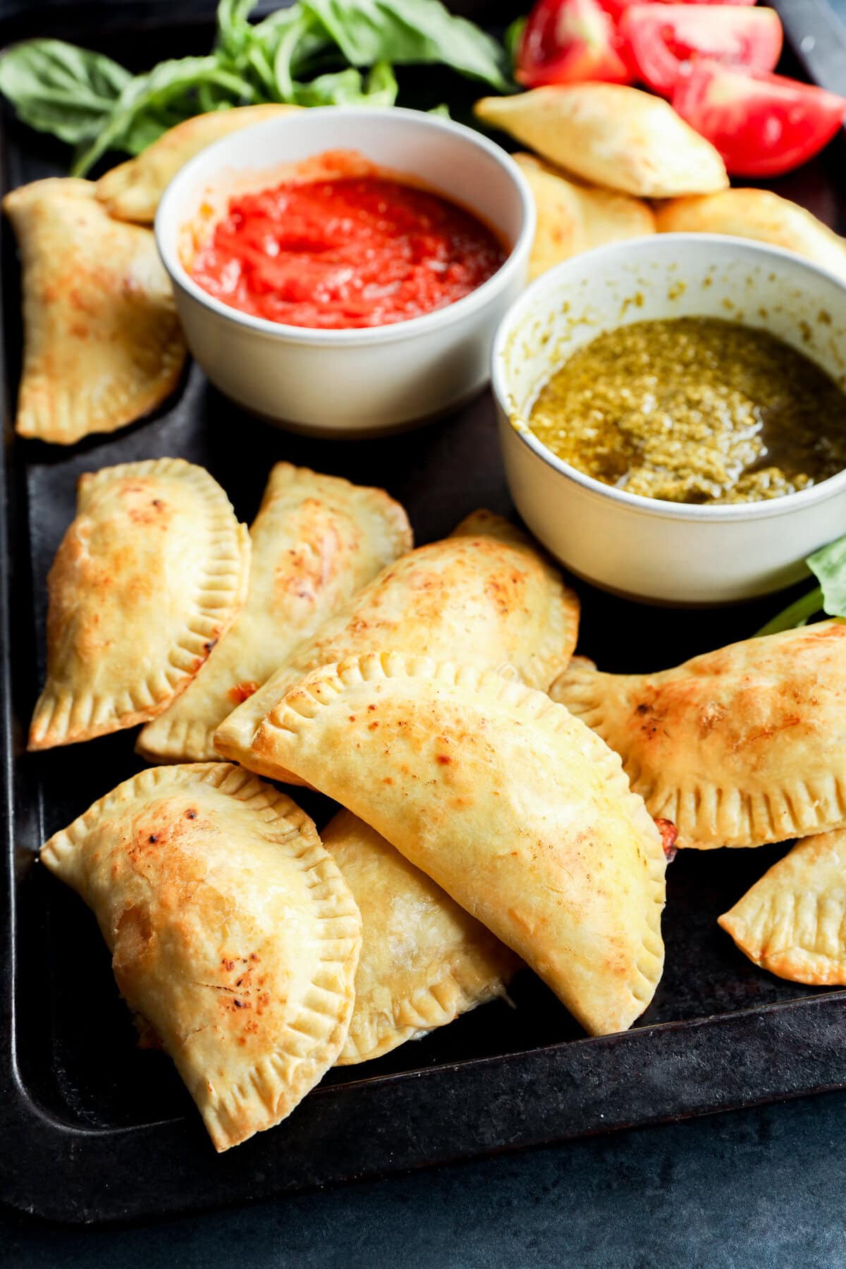 easy pastries on sheet pan with dipping sauces and tomatoes and basil