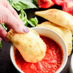 dipping pastry filled with mozzarella, basil, and tomato into marinara sauce