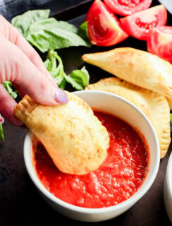 dipping pastry filled with mozzarella, basil, and tomato into marinara sauce