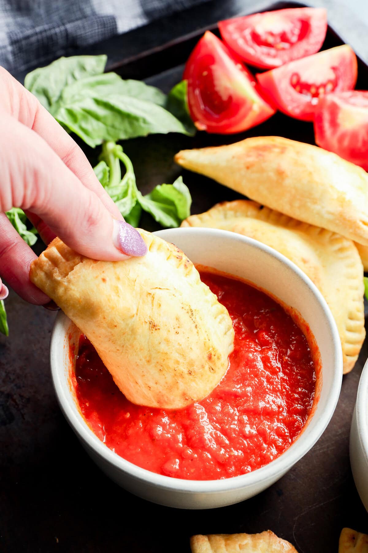 dipping pastry filled with mozzarella, basil, and tomato into marinara sauce