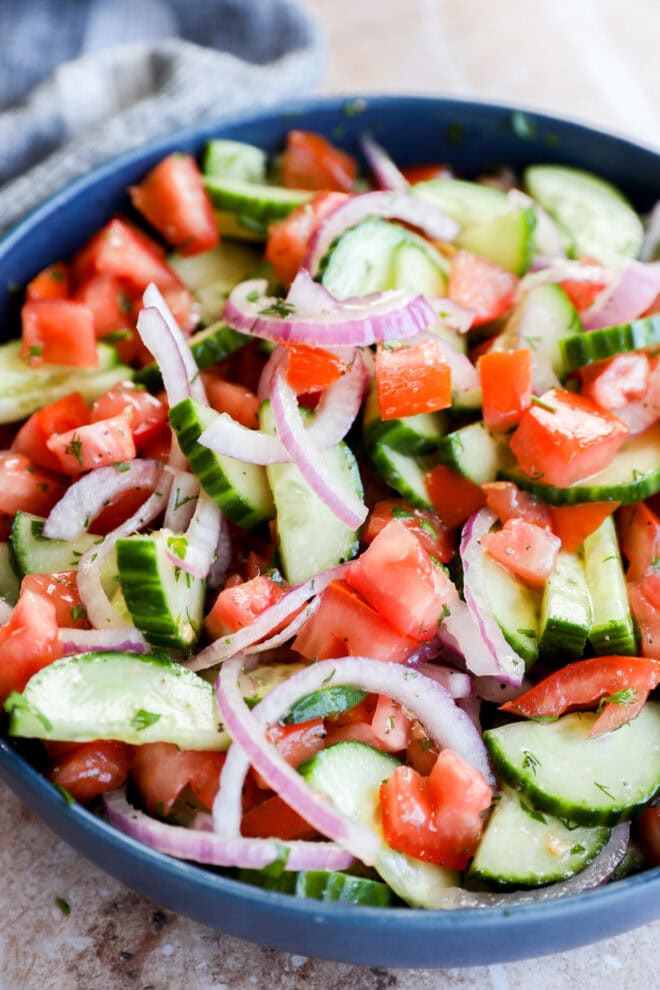 Cucumber tomato salad in a bowl with fresh herbs and tangy dressing