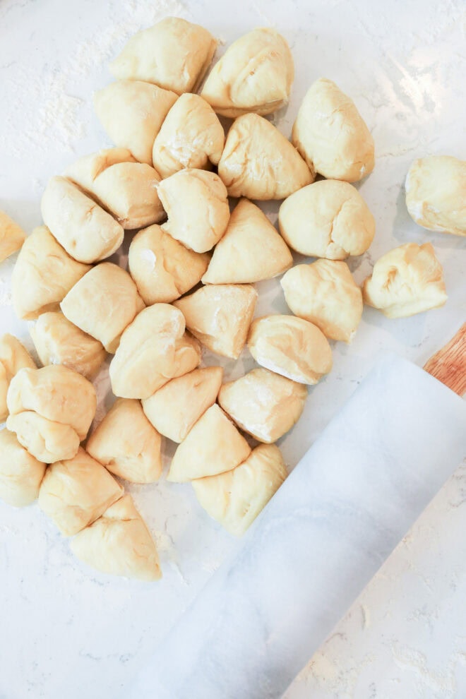 empanada dough balls next to rolling pin on marble