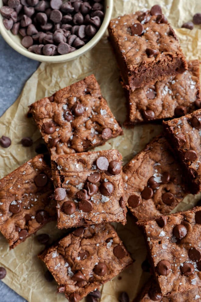 chocolate chocolate chip cookie bars with a bowl of chocolate chips on parchment paper
